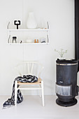 Swedish stove and classic chair under a shelf in a white living room