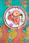 Three flat peaches on a plate and patterned tablecloth