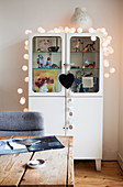Fairy lights on a white retro showcase with pictures and figures of children
