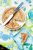 Sliced quiche on a table with a summery floral tablecloth