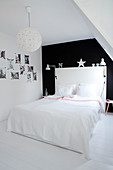 White double bed with headboard against black wall in bedroom