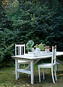Tablett mit weißen Übertöpfen und Pflanzen auf einem Tisch im Garten