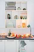 Cotton ball fairy lights on kitchen worksurface below ornaments on shelves