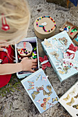 Child rummages in boxes of crafting materials on the beach