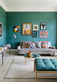 A picture gallery above a sofa in a living room with petrol blue walls