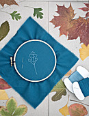 Blue fabric with leaf motif embroidered on an embroidery hoop