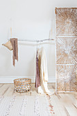 Hanging branch on wooden bead chains as a clothes rail next to a screen