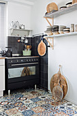Mediterranean kitchen with patterned tiled floor and black stove