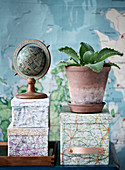 Globe and alligator plant on boxes decorated with maps pasted on it