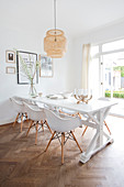 Cane lamp above the dining table with shell chairs on herringbone parquet