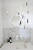Mobile made of feathers and a hexagonal mirror over the sink