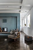 Cosy chair on concrete floor in front of fireplace with blue wall