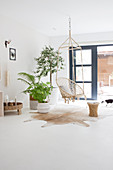 Hanging chair and houseplants in front of the patio door in a white living room