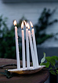Dünne weiße Kerzen in einer Muschel als Gartendeko