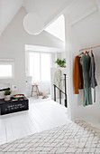 Clothes rail, vintage box, and stool in front of a window in the bright attic
