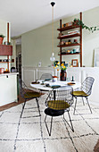 Wire chairs around a dining table on a rug in open-plan kitchen