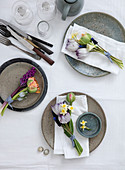 Tulpen, Hyazinthen, Narzissen und Traubenhyazinthen in kleinen Sträußen auf Tellern