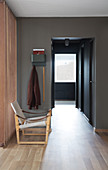 A designer chair in front of a teak wall in a hallway