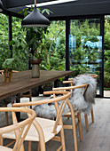 A homemade wooden dining table with classic chairs in a conservatory