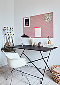 A filigree table and a white classic chair in front of a pinboard