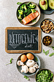 Ketogenic diet ingredients for cooking dinner. Raw salmon, avocado, broccoli, bean, olives, nuts, mushrooms, eggs in ceramic bowls