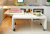 Modern white coffee table on castors fits under the sideboard to save space