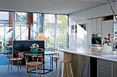 Bistro chairs at a round glass table in front of an open-plan kitchen