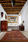 Oriental carpet in the rustic living room with wooden beam ceiling