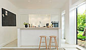 Bar stools at a kitchen counter next to an open garden door