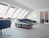 Upholstered stool on castors as a room divider in the living room with skylights