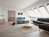 Katze im modernen Wohnzimmer unter der Schräge mit einer Reihe Dachenster