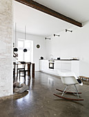 Rocking chair in an open living room with kitchenette and concrete floor