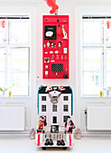 Red type case over dollhouse between two windows