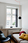 Helle Couch und schwarzer Designerstuhl vor Fenster im Wohnzimmer