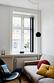 Light couch and black designer chair in front of the window in a living room