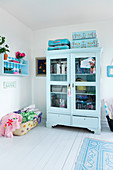 Light blue display cabinet with books, seat cushions, and suitcases