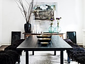 Black dining table with bowls and benches with black fur in the dining area