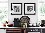 Black and white photos on the wall and pendant lights above the kitchen unit