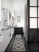 Waschtisch im Badezimmer mit weißen Wänden und schwarz lackiertem Dielenboden