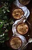 Porridge mit Zimt in Schalen neben Jasminblüten