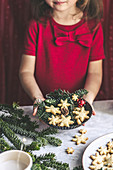 Kind hält Teller mit Kokos-Schneeflockenplätzchen in den Händen