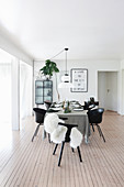 Table set with grey tablecloth and black chairs on wooden floor