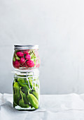 Pickled chili peppers and radishes in glass jars