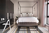 Modern four-poster bed in bedroom in shades of grey