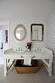White double washstand below antique mirrors on tiled wall