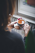 A woman with a hot tea and spiced biscuits
