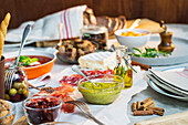 An arrangement of appetisers featuring meat, cold cuts, vegetables and a dip