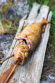 Smoked skewered fish outside on a plank of wood