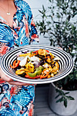 A woman holding a serving platter of grilled vegetables