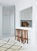 Wooden stool in front of serving hatch between kitchen and dining room